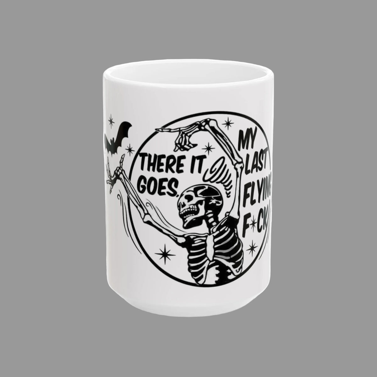 A white ceramic mug featuring a black graphic of a skeleton holding a bat, with the text 'MY LAST FLYING F*CK' and 'THERE IT GOES' inside a circular design.