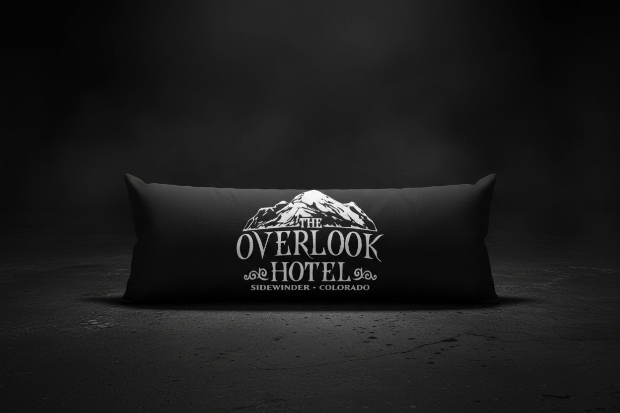 A long rectangular black pillow featuring a white graphic print of a mountain and the text 'THE OVERLOOK HOTEL' and 'SIDWINGER - COLORADO'.