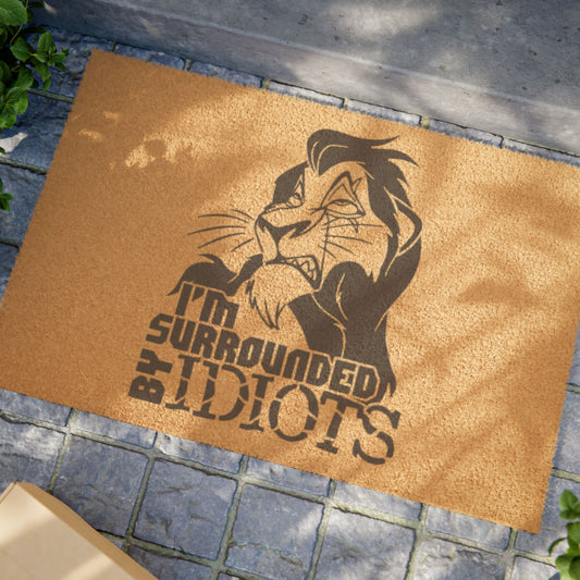 Doormat with character design and text 'I'm Surrounded by Idiots' on a textured surface.